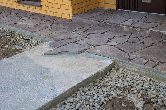 Finished irregular flagstone walkway beside brick house, residential landscaping, hardscaping and exterior renovation.