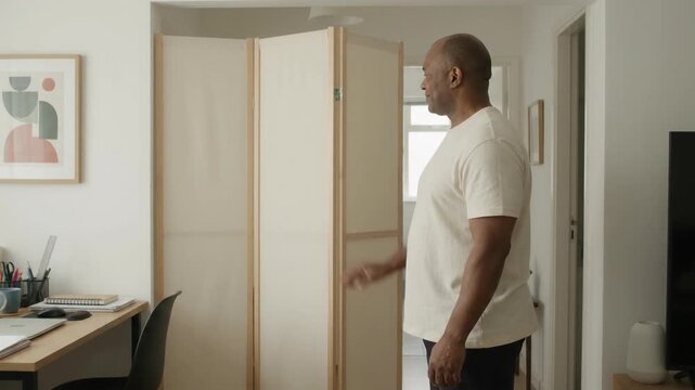 Man Adjusting Folding Room Divider Screen in Home Office