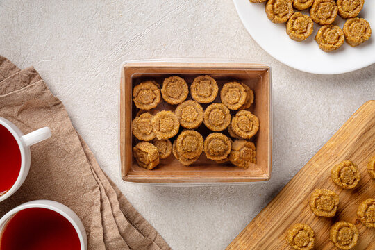 Overhead shot of traditional Kazakh confection zhent made of roasted grain and nuts served in a brown paper takeout box with red tea