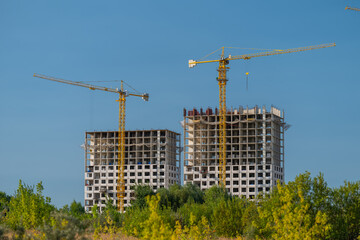 Construction of modern high-rise buildings in a vibrant urban landscape under a clear blue sky © beholdereye