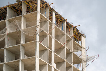 New skyscraper rises against a cloudy sky in an urban landscape showcasing the modern construction techniques and materials used in today's building designs © beholdereye