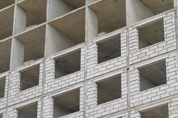 Construction progress of a modern building shows concrete frames and brick work during daylight hours © beholdereye