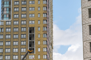 Construction site bustling with activity as cranes work on a high-rise building in a modern urban setting under a bright sky © beholdereye