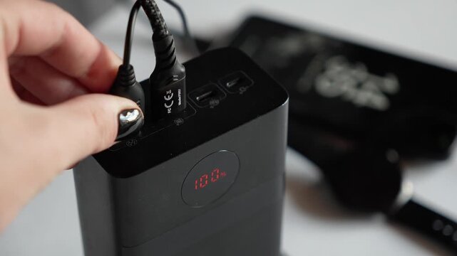 Connecting a USB Type-A cable to a power bank. Sleek black portable power banks charging gadgets&mdash;a smartphone and a smartwatch. A concept representing modern gadgets and technology