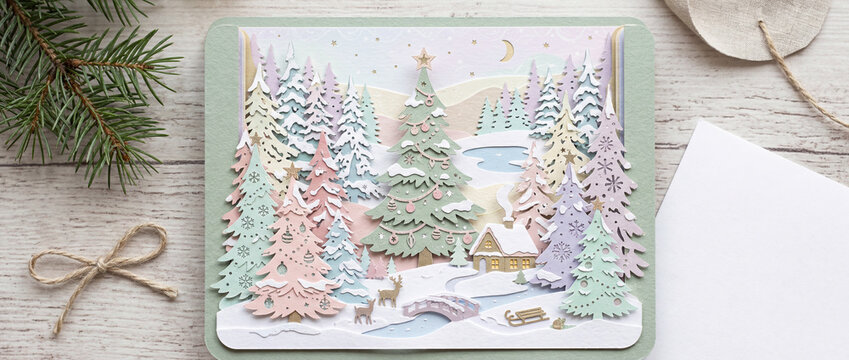 Handmade christmas card with papercraft snow covered forest winter scene. Holiday craft banner with copy space.