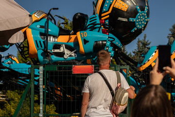 A middle-aged man at an amusement park. He is standing in front of the ride, waiting for his child. © Mikhail