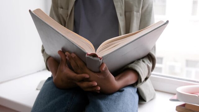 woman reading a book. Person Reading a Book Indoors. people, season and leisure concept - close up of woman in warm sweater reading book at home. 