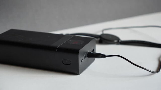 Connecting a USB Type-A cable to a power bank. Sleek black portable power banks charging gadgets and smartwatches. Concept of modern gadgets and technology. Backup power, electricity, energy storage