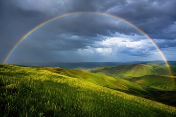 Obraz premium Rainbow arching over wet green rolling hills