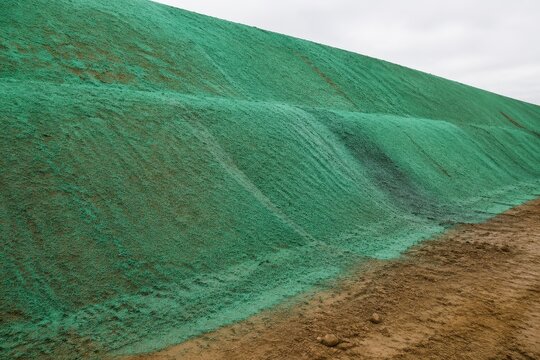 Bare soil embankment sprayed with a green mulch binding coat