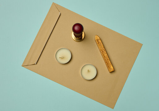 Craft envelope, wax seal, candles, and sealing wax stick on a turquoise background.