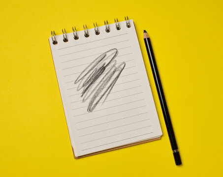 Spiral-bound lined notepad with a black pencil and a scribbled drawing on a bright yellow background.
