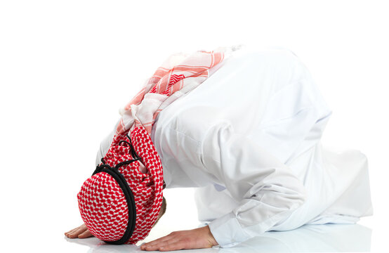 Muslim Arab man in traditional clothing prostrating in Islamic prayer sujud position isolated on white background.