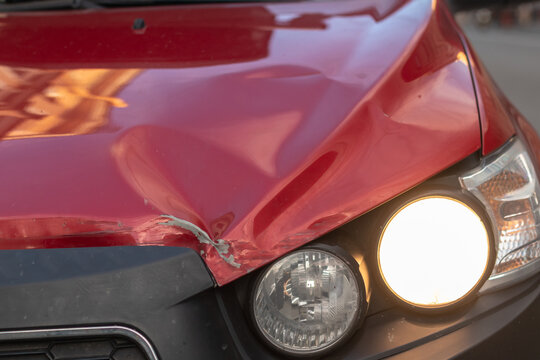 Damaged red car with a broken headlight
