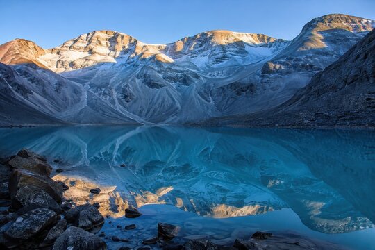 Turquoise mountain lake below a jagged alpine ridge at dawn