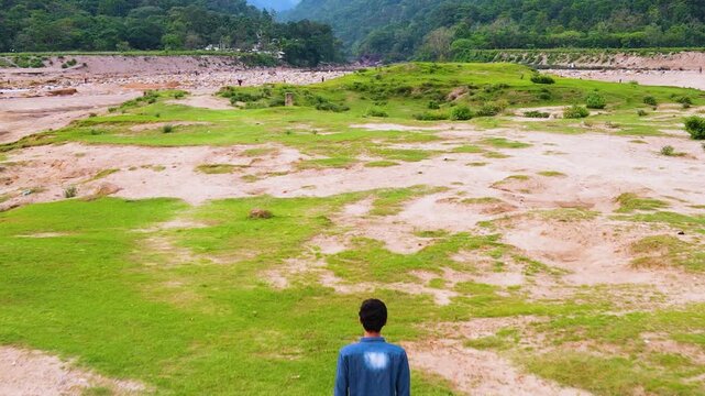A Man Walks Toward The Forested Khasi Hills At Bichanakandi In Sylhet, Near The Bangladesh-India Border. Tilt-up Shot