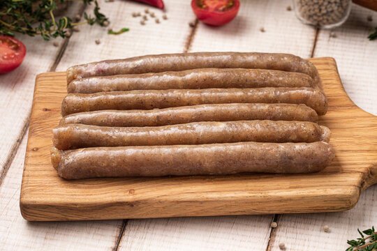 Raw chicken sausages arranged neatly on wooden cutting board ready for cooking