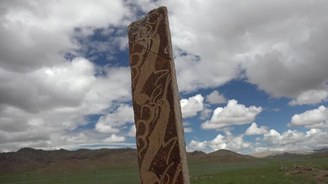Asian deer stone monument bears ritual symbols on an ancient burial stele in open steppe.