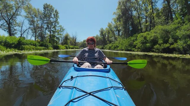 Mature couple in tandem kayak resting and drifting on calm river POV