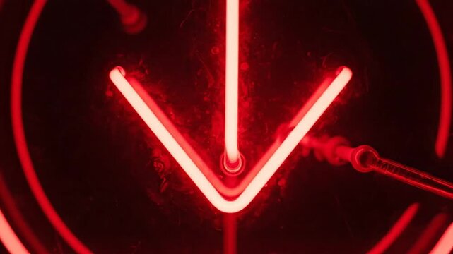 Bright red neon down arrow sign glowing on a dark background
