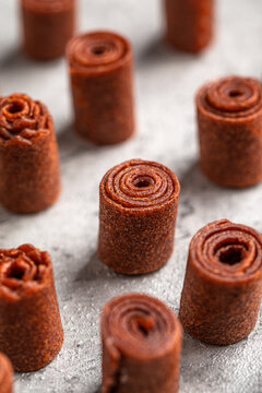 Appetizing sweet fruit leather rolls arranged in neat columns showing spiral texture on grey surface closeup