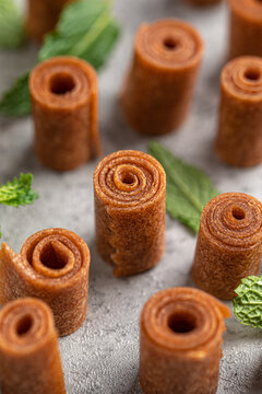 Appetizing sweet fruit leather rolls arranged in neat columns showing spiral texture on grey surface closeup