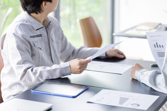 資料を確認しながら打ち合わせをする日本人の作業員