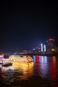 Chongqing, China - July 19, 2026: Chongqing city nighttime view of illuminated skyline and tourist boat for cruise on the river in Chongqing, China.