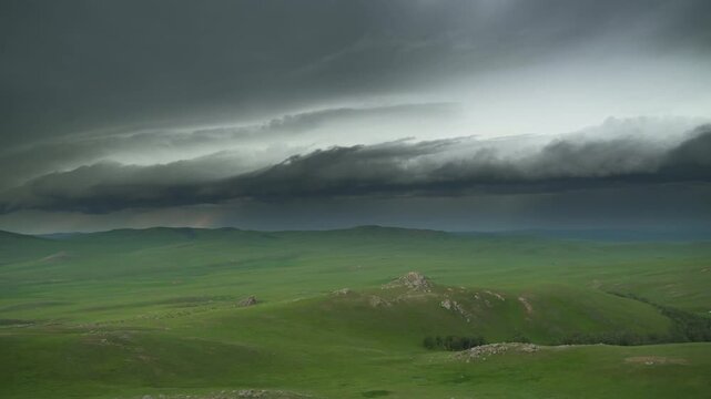 Rotating supercell storm clouds loom over green plains as a rain curtain forms ahead.