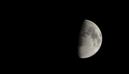 First Quarter Moon Against Black Night Sky with Detailed Lunar Craters © roobcio