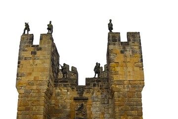 Looking up at high medieval stone castle walls and towers against white sky. Historic fortress architecture, ancient defensive structure. Alnwick castle England © TomKorcak