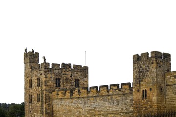 Looking up at high medieval stone castle walls and towers against white sky. Historic fortress architecture, ancient defensive structure. Alnwick castle England © TomKorcak