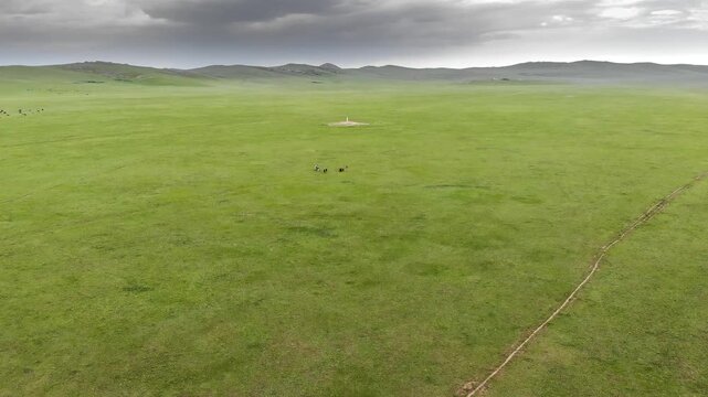 Stone kurgan and sacred stele stand on Mongolia steppe as ancient burial monument.