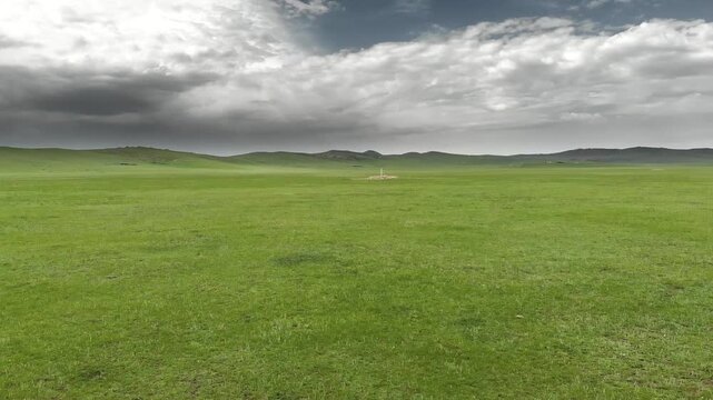 Stone kurgan and sacred stele stand on Mongolia steppe as ancient burial monument.