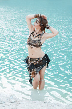 Pretty woman in tribal style on white sand beach near the water