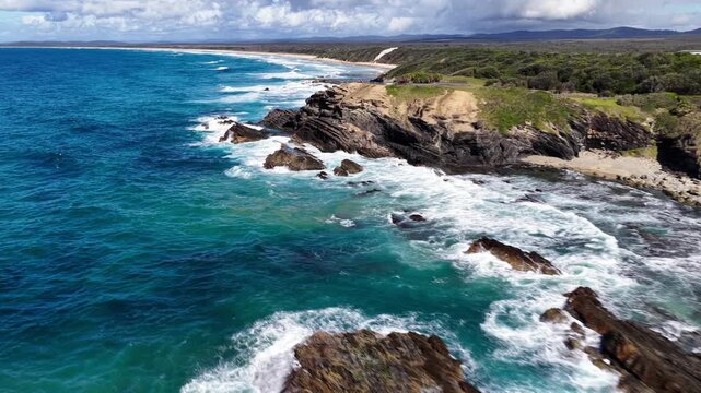 Aerial video showcasing turquoise ocean water, breaking waves and rugged rock formations along the coastline at Brooms Head on the NSW North Coast, Australia.