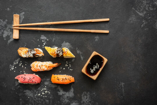 Set of Japanese sushi with soy sauce and chopsticks on a black stone background, top view, flat lay, copy space