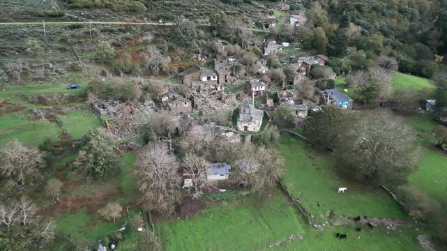 Aerial view over the ruins and green clearings of Santoalla do Monte in Galicia, Spain, showing the remains of the remote settlement surrounded by mountainous countryside