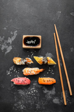 Set of Japanese sushi with soy sauce and chopsticks on a black stone background, top view, flat lay, copy space, vertical