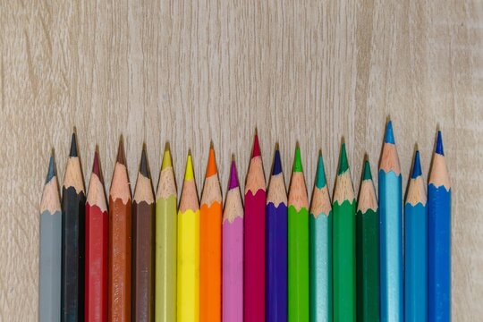 A row of sharpened colored pencils on a wooden table