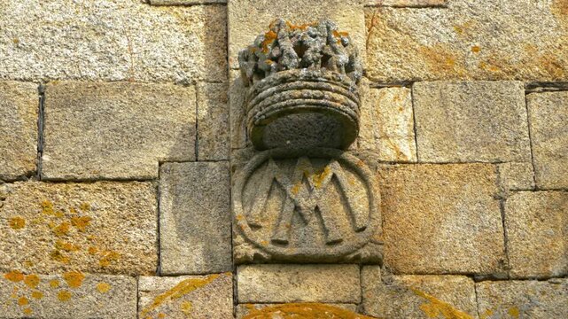 Close-up of a weathered carved stone ornament on the historic Church of Santa Mar&iacute;a de Mones in Pet&iacute;n, Galicia, Spain, highlighting traditional masonry and religious craftsmanship.