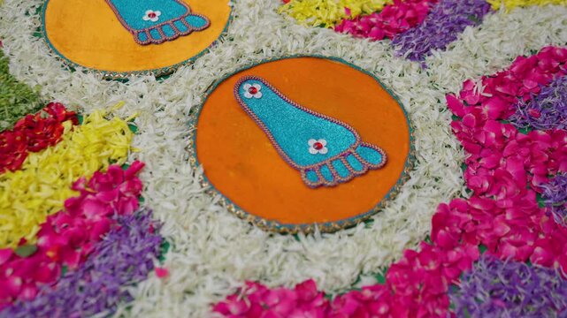 Close-up of glittering blue footprint rangoli circles bordered by flowers at a South Indian Karnataka wedding ceremony during Saptapadi ritual.