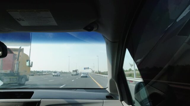 Driving along multi-lane Dubai UAE highway with trucks and cars, seen from inside vehicle