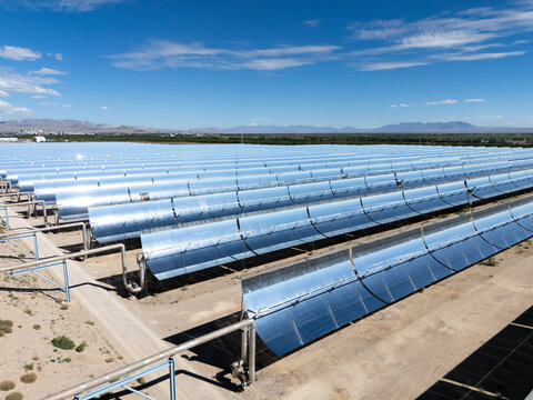 concentrated solar power plant with parabolic trough mirrors under blue sky