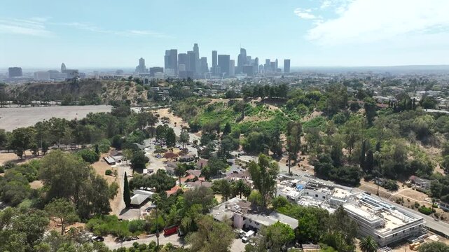Los Angeles, California, USA - Pullback aerial drone view over Elysian Park near Stadium Way featuring the famous DTLA skyline in the distance. The footage captures Downtown skyscrapers, gr