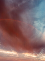 Obraz premium Faint Rainbow Beneath Dramatic Storm Clouds After Rain at Sunrise