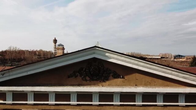 An old Soviet-era building with a walkway leading to an abandoned factory.