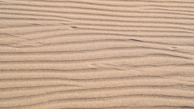 Close view of desert sand ripples and dune patterns across a barren empty landscape.