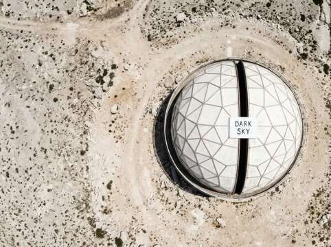 Geodesic observatory dome in arid landscape with dark sky sign