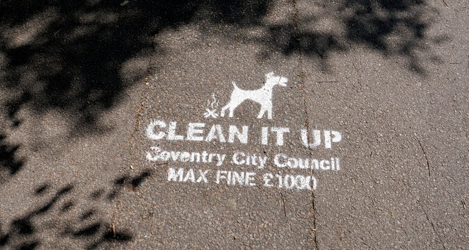 Clean it up stencil sign on asphalt road, dog fouling warning, Coventry City Council max fine sign on pavement
